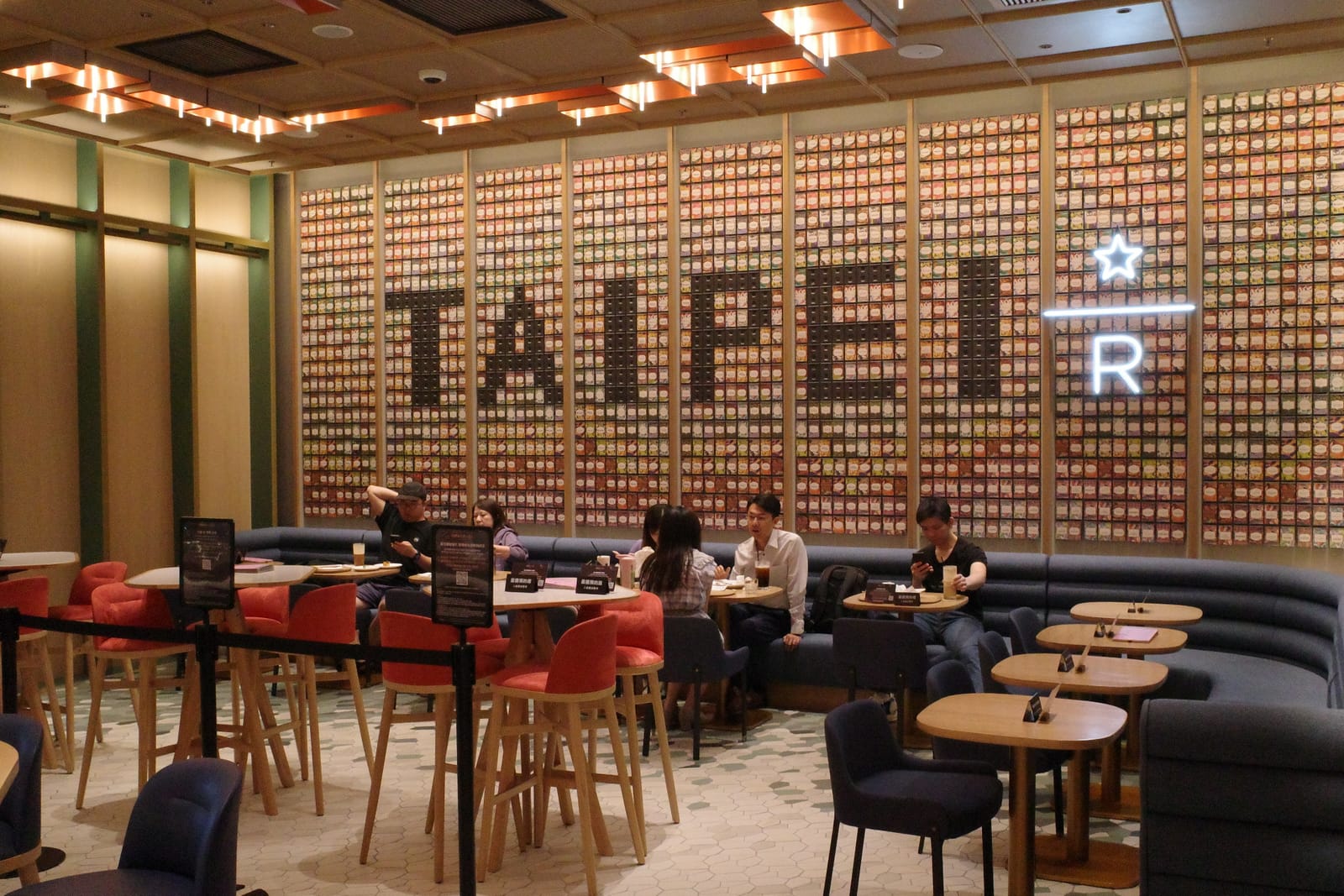「TAIPEI」の文字と Reserve の R マークが描かれた格子状の壁、その手前に赤・青・オレンジのチェアとソファ席