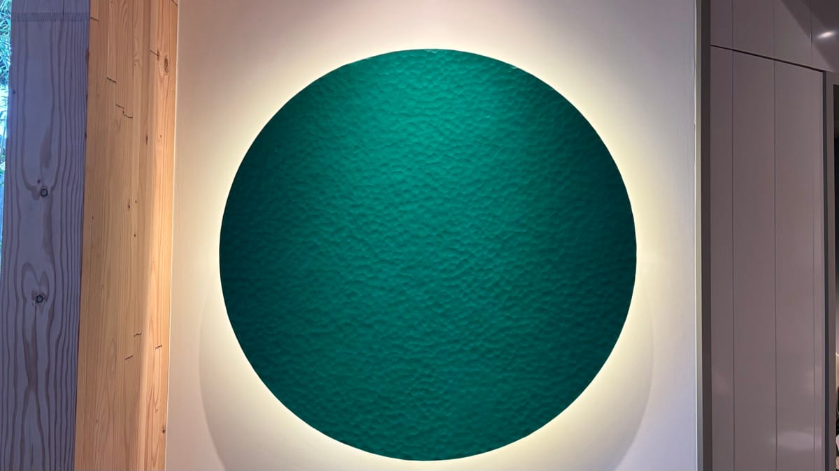 グリーンの円形作品。背面のライトで浮かび上がるように展示されている
